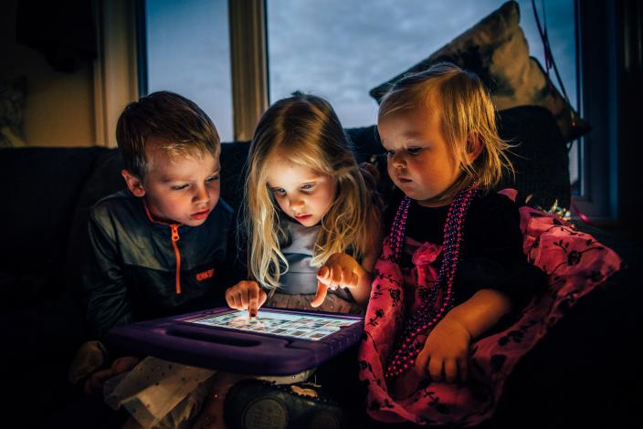 Three children looking at a tablet