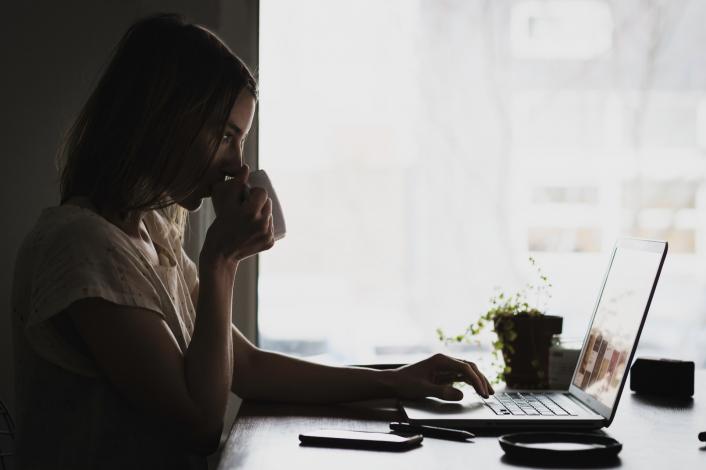 Woman drinking coffee at computer