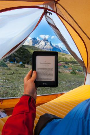Person holding Kindle in tent