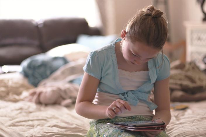 Girl sitting on bed using tablet