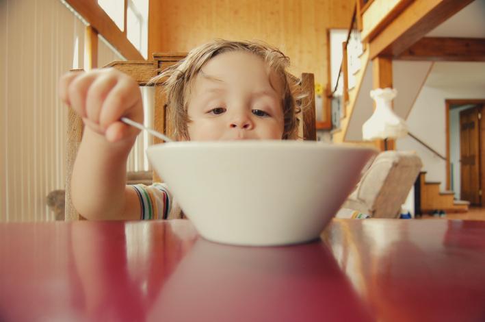 Child behind bowl with spoon