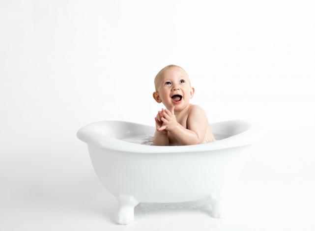 Happy baby in small bathtub