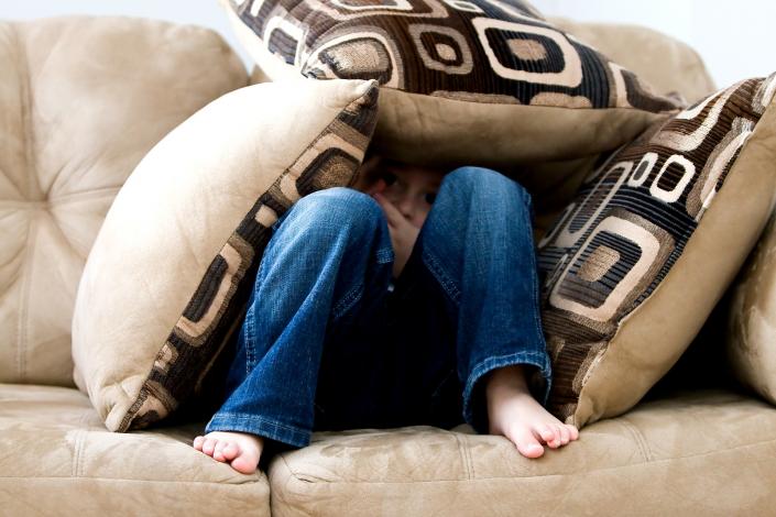 Little boy under couch pillows