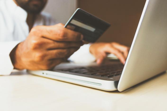 Person holding credit card by computer