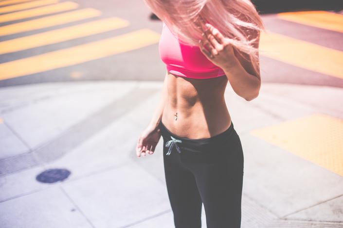 Woman wearing pink sports bra and showing off abs