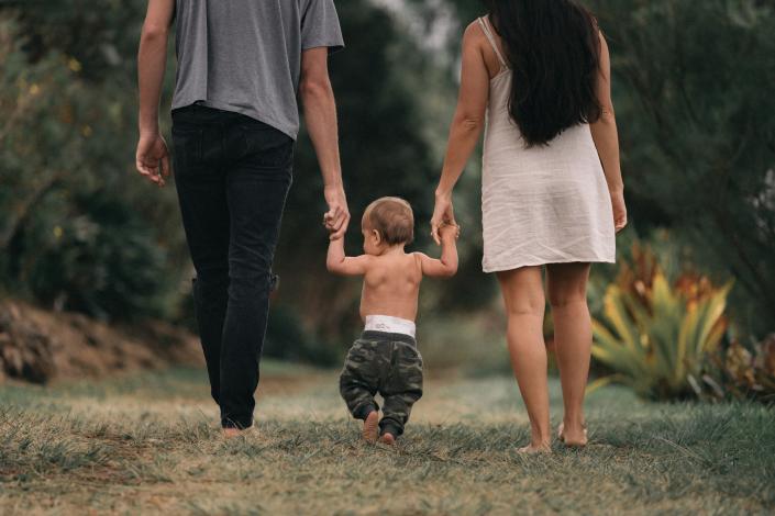 Baby walking with mom and dad