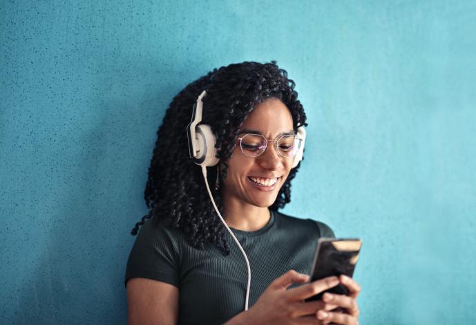 Woman wearing headphones, holding phone