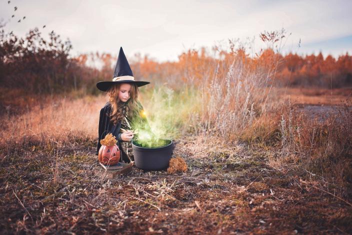 Girl in witch costume by cauldron