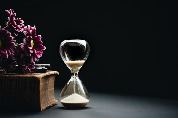 Hourglass sitting next to flowers