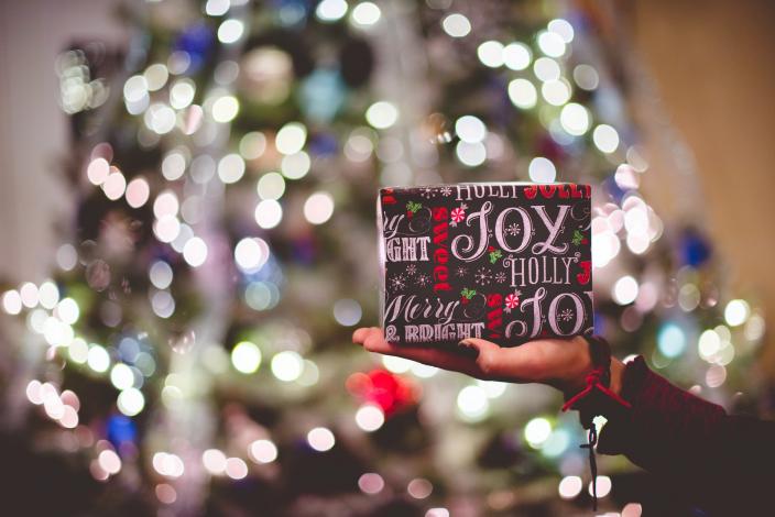 Christmas gift being held in front of tree