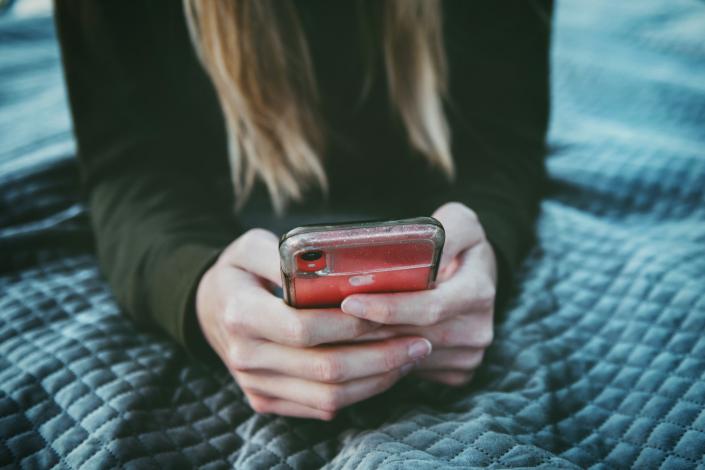 Person holding phone on bed