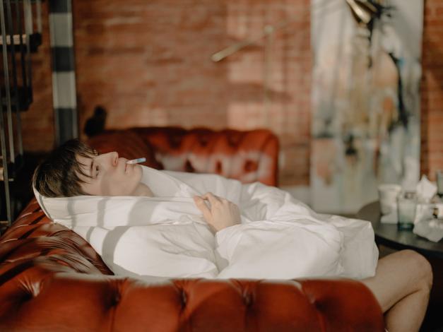 Man on couch with thermometer
