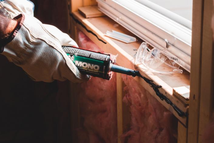 Person putting caulk around window