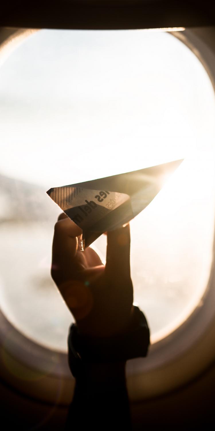 Paper airplane in front of plane window