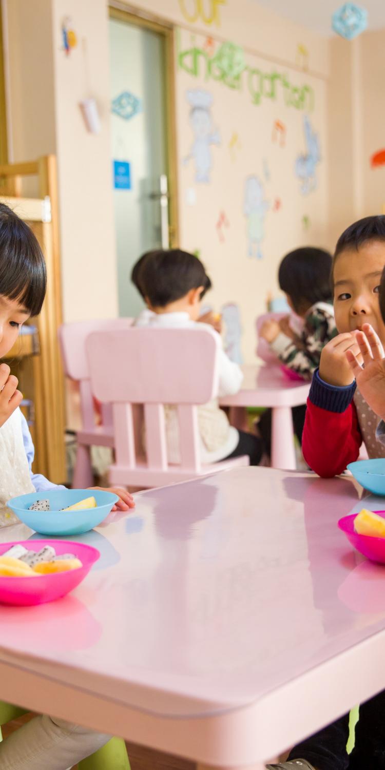 Three toddlers eating on a white table