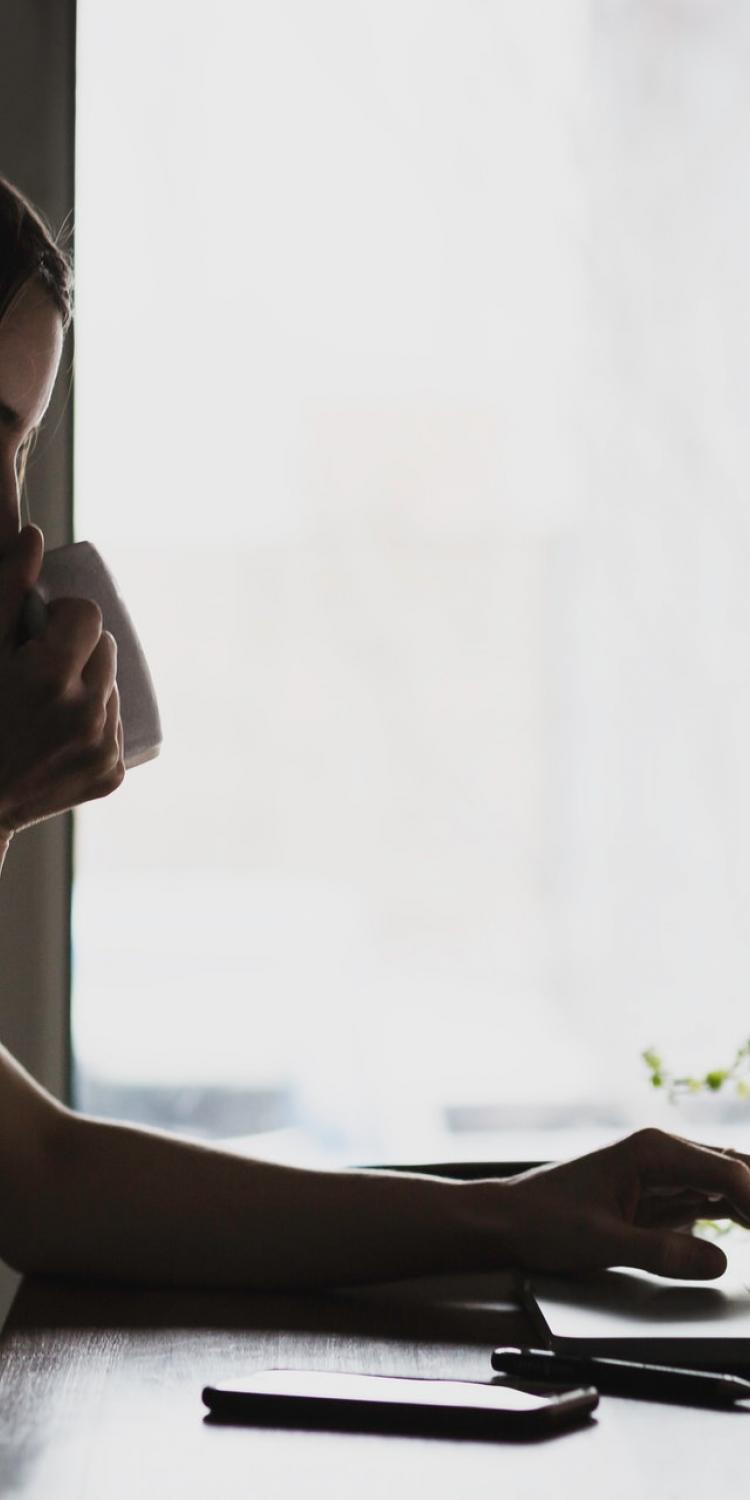 Woman drinking coffee at computer