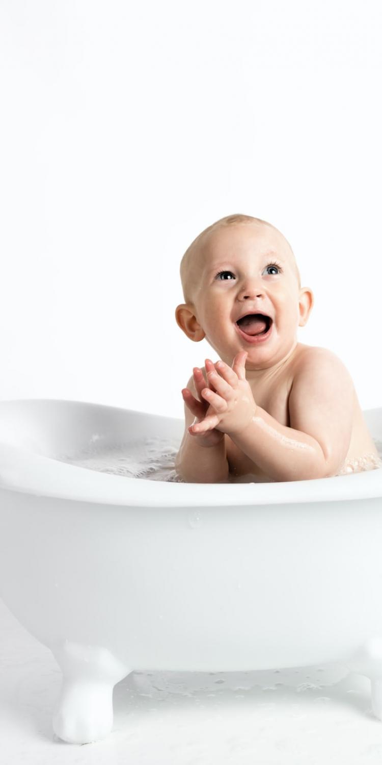 Happy baby in small bathtub