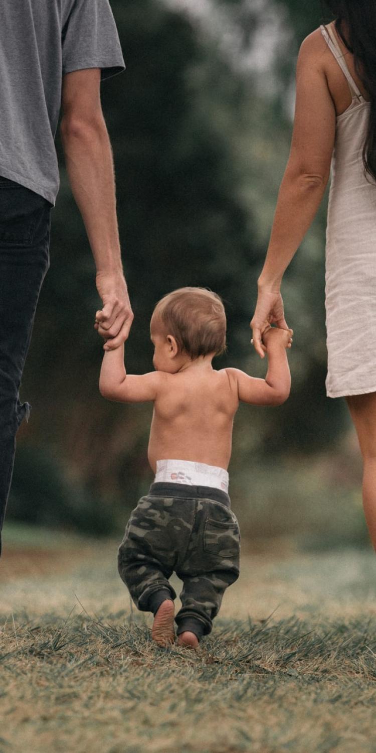 Baby walking with mom and dad