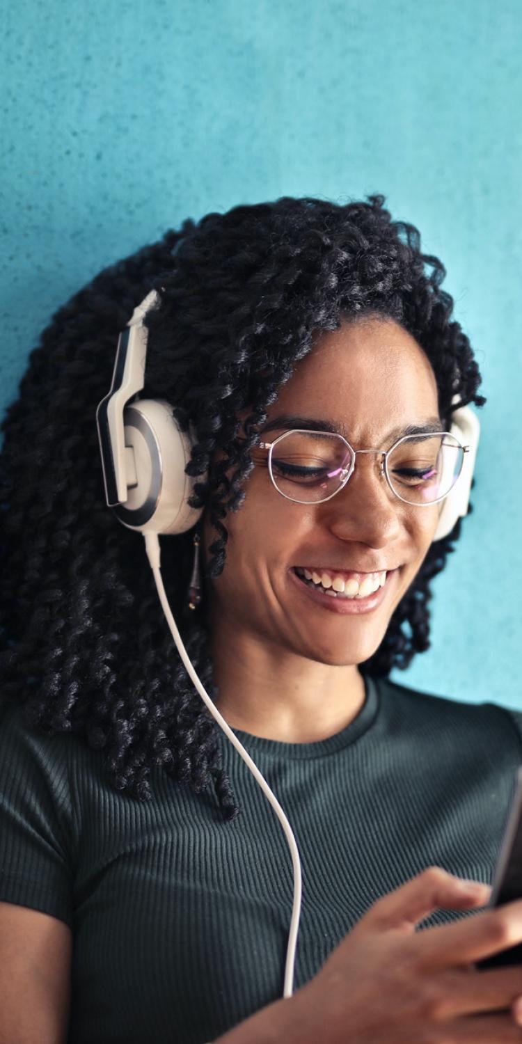 Woman wearing headphones, holding phone