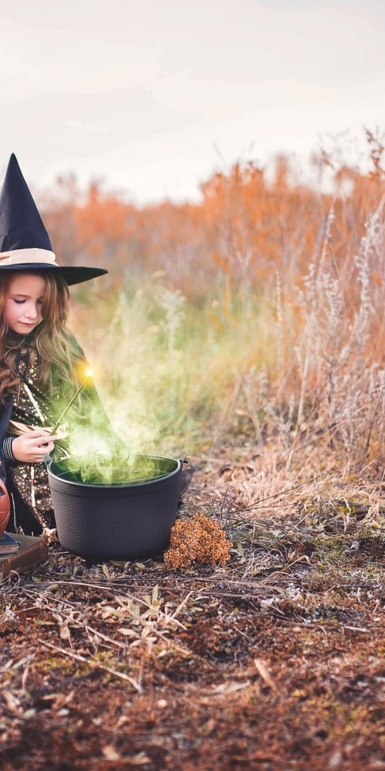 Girl in witch costume by cauldron