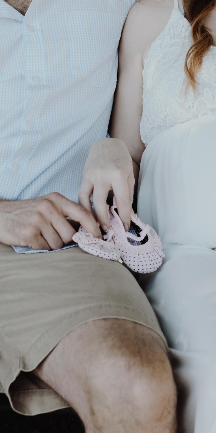 Adults holding baby shoes