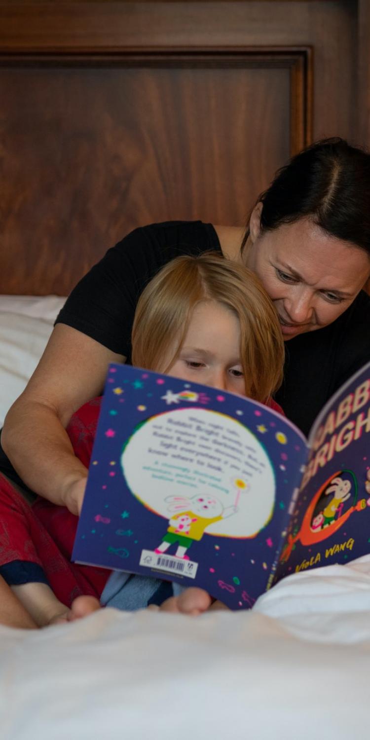 Woman reading to child in bed
