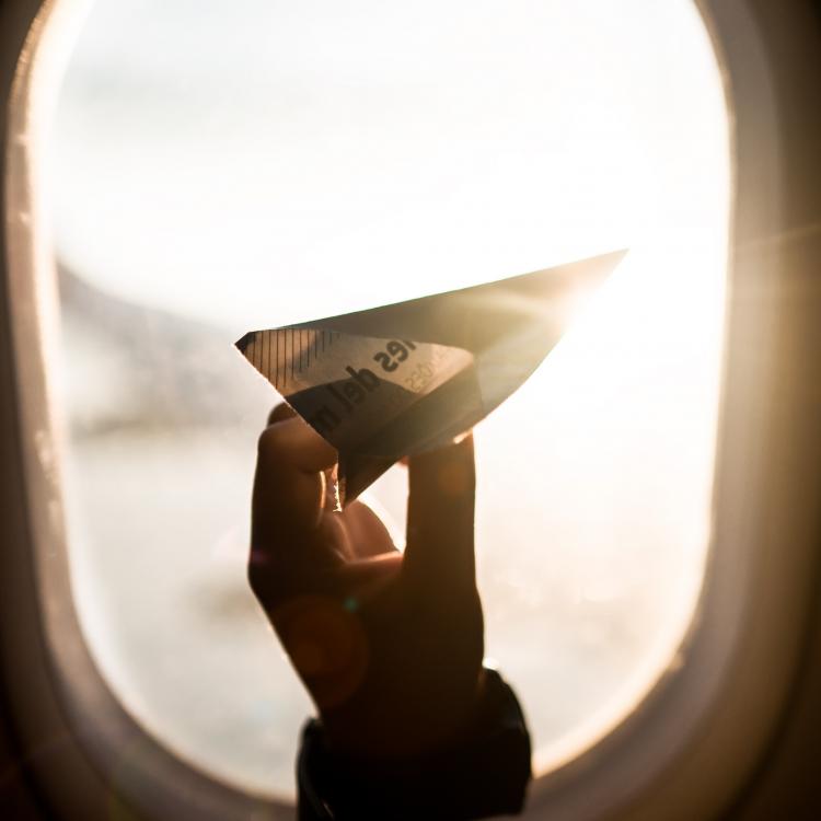 Paper airplane in front of plane window