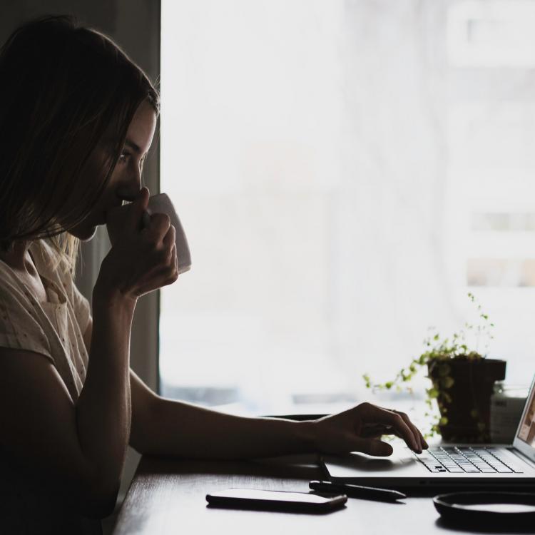 Woman drinking coffee at computer